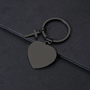 Detalle de llaveros de metal cruz y corazón en negro mate sobre una superficie