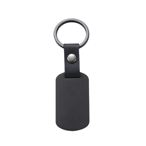 Close-up of black matte metal military tag and textured leather keychain connector