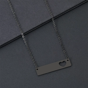 Collier barre noir mat minimaliste avec découpe en cœur sur fond texturé élégant