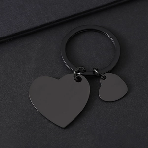 Detalle de dos colgantes de metal en forma de corazón negro pulido para grabado láser