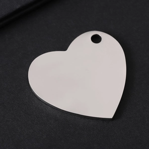 Close-up of polished heart-shaped stainless steel tag with single hole on black background