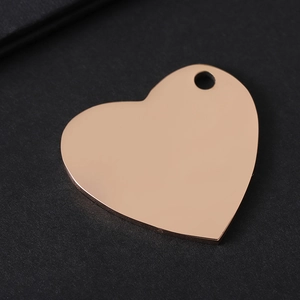 Polished rose gold heart-shaped metal tag with hole on dark textured background