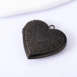 Detail of vintage gunmetal heart locket with floral engraving and hinge structure