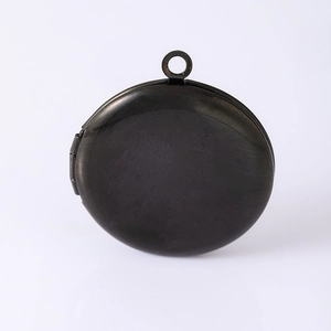 Macro detail of a round black metal locket pendant with a matte brushed finish