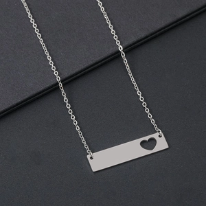 Collier avec barre en acier inoxydable argenté et détail de coeur sur fond noir élégant
