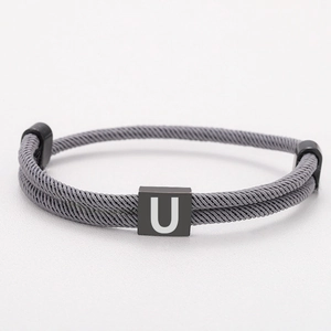 Close-up of grey Milanese rope bracelet with adjustable black square letter U charm