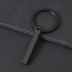 Close-up of minimalist black stainless steel rectangular bar pendant on a matte key ring