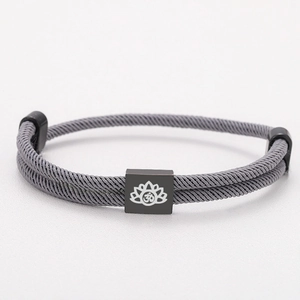 Detail of grey braided cord bracelet featuring a black square charm with white lotus and Om