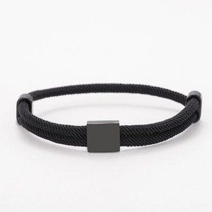 Detail of minimalist black woven cord bracelet featuring a matte metal rectangle charm