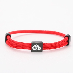 Red braided cord bracelet with black square metal charm featuring a white lotus Om symbol