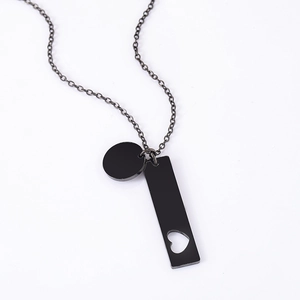Macro detail of black stainless steel pendant with hollow heart cutout and round disc