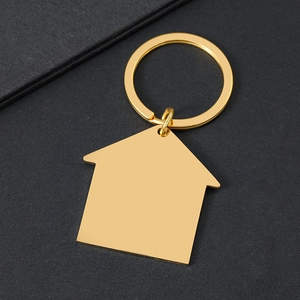 Polierter goldener Schlüsselanhänger in Hausform auf minimalistischem schwarzem Grund