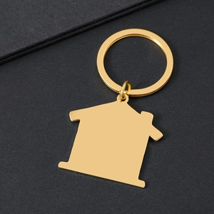 Polished gold house-shaped stainless steel keychain on dark textured background