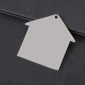 Close-up of house-shaped stainless steel pendant with polished finish on black background