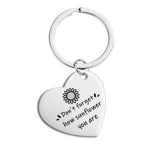Detail of sunflower engraved heart keychain with inspirational quote on polished steel