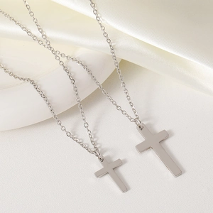 Polished stainless steel cross pendants on delicate O-chains over white silk fabric