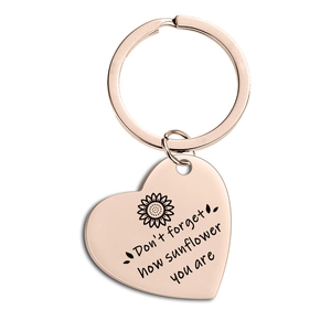 Close-up of rose gold heart keychain with sunflower design and motivational engraving