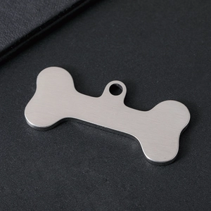 Macro shot of bone-shaped pet ID tag in brushed stainless steel with engraving detail