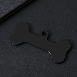 Detail view of bone-shaped pet ID tag with matte black metal finish and round hanging hole