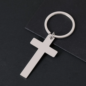 Detailed view of polished stainless steel cross pendant keychain on black textured card