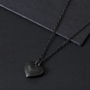 Macro detail of polished black heart pendant on a fine stainless steel cross chain