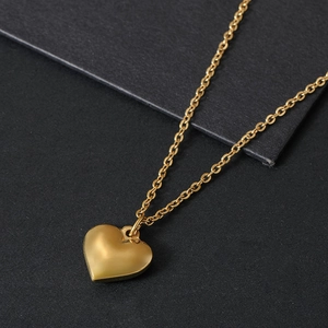 Golden heart pendant necklace with matte finish on elegant grey textured background