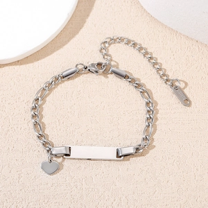 Detailed macro view of silver stainless steel Cuban chain bracelet with heart charm and ID plate