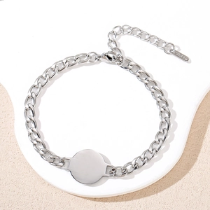 Macro shot of stainless steel Cuban chain bracelet with blank round charm and lobster clasp