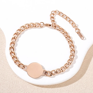 Polished rose gold Cuban chain bracelet with a round tag on white display stand