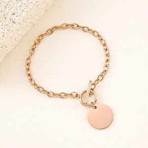 Detail view of a rose gold chain bracelet with OT toggle clasp and smooth round pendant