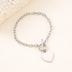 Polished stainless steel toggle bracelet with heart pendant on textured backdrop