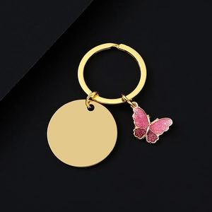 Detail of gold keychain with pink glitter butterfly charm and round engraving plate