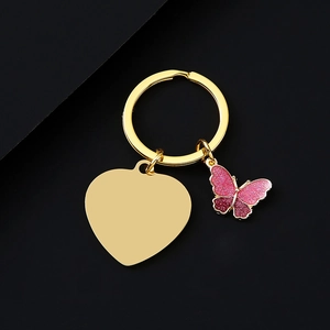 Macro shot of gold heart keychain with pink glitter butterfly charm on black background