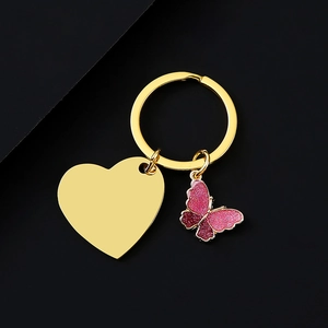Detail of a gold heart charm and pink glittery butterfly pendant on a sleek keychain