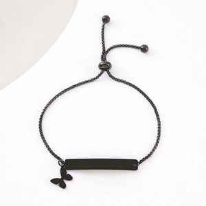 Macro detail of black stainless steel ID bracelet with butterfly charm and slider buckle