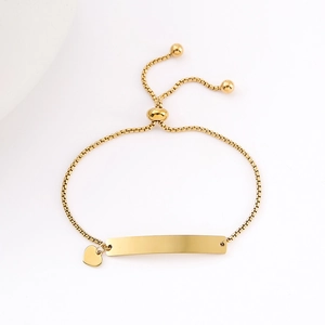 Polished gold stainless steel box chain bracelet featuring a curved ID bar and heart charm