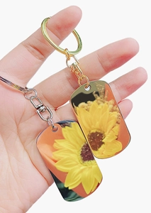 Close-up of golden metal keychain featuring vibrant sunflower patterns and sturdy lobster clasp
