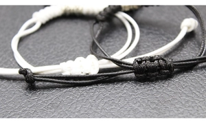 Detail of adjustable couple woven bracelets with silver beads on black leather surface