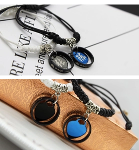 Detail of woven couple bracelets with silver rings featuring Love and heart engravings