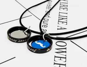 Detail of couple necklace pendants featuring forever love engraving and beard motif