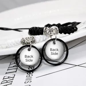 Matching black and white woven rope bracelets for couples with round silver pendants