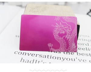 Macro detail of laser engraved dragon motif on a 0.2mm rose red metallic business card