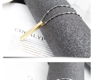 Close-up of golden stainless steel vertical cuboid pendant on silver twisted metal chain