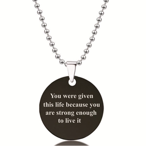 Detail van ronde zwarte hanger met inspirerende tekst aan een bolletjesketting