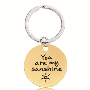 Gros plan du porte-clés doré en acier inoxydable gravé You are my sunshine et motif soleil