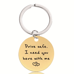 Détail du porte-clés rond doré avec gravure de cœurs et message Drive Safe