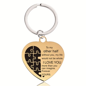 Detail of golden stainless steel heart keychain with puzzle piece and engraved text