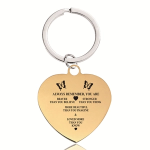 Detailed close-up of golden heart keychain with engraved inspirational quote and butterflies