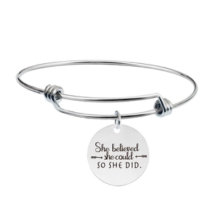 Close-up of adjustable silver bangle with engraved round pendant She believed she could