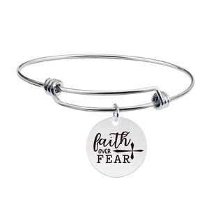 Detail view of stainless steel bangle featuring engraved faith OVER FEAR round pendant charm